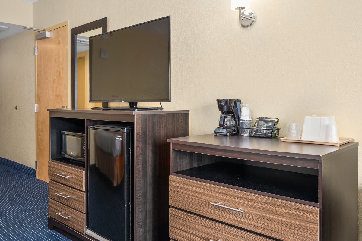 a hotel room with a television, refrigerator and coffee maker