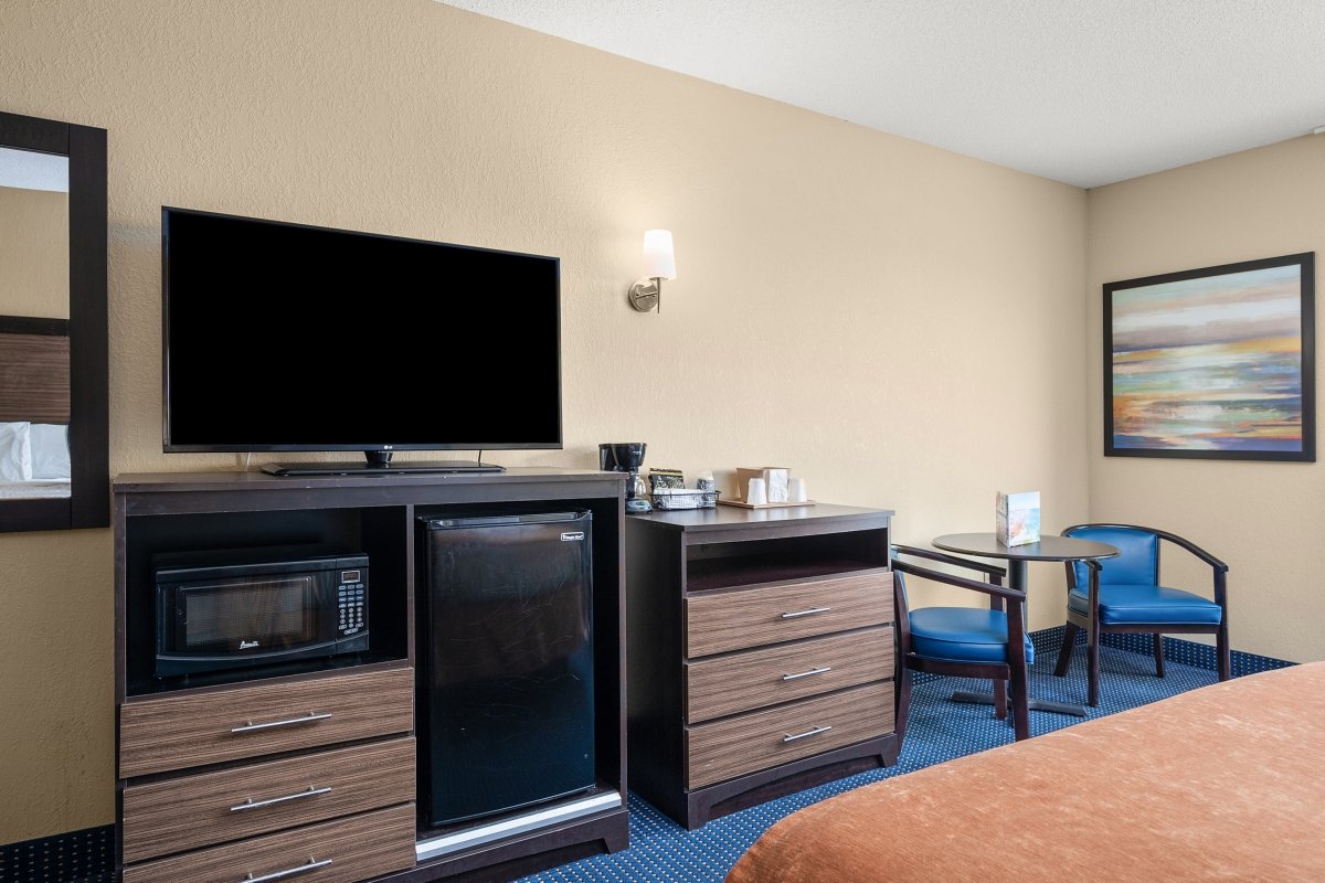 a hotel room with a bed, desk and television