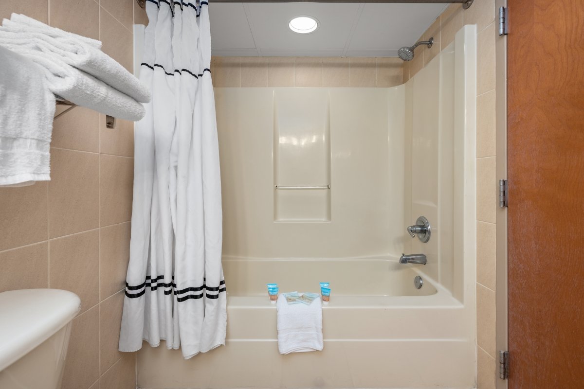 a bathroom with a bathtub, shower curtain and towels