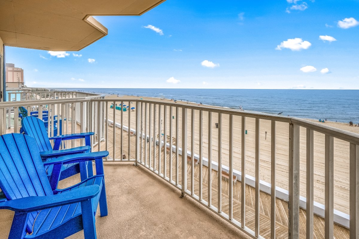 two blue chairs sitting on top of a balcony next to the ocean