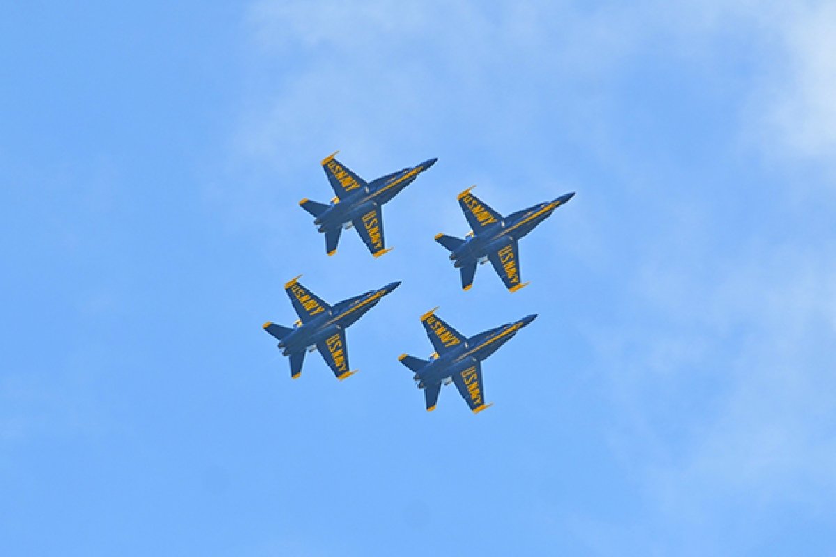 four fighter jets flying in formation against a blue sky