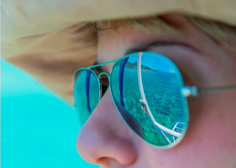 a person wearing sunglasses with the reflection of a beach in them