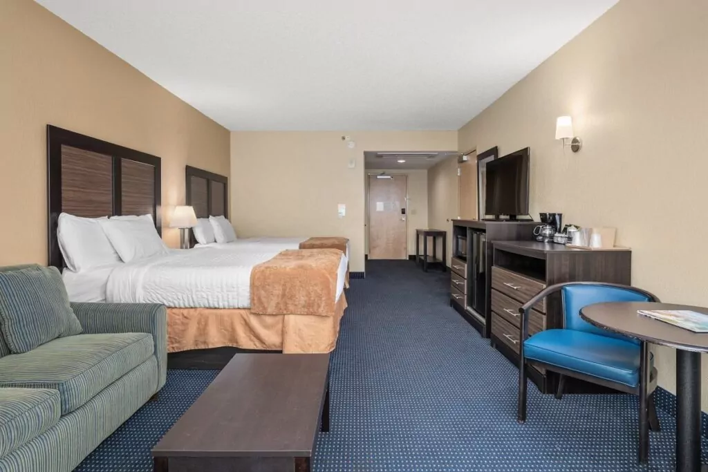 a hotel room with a couch, desk and television